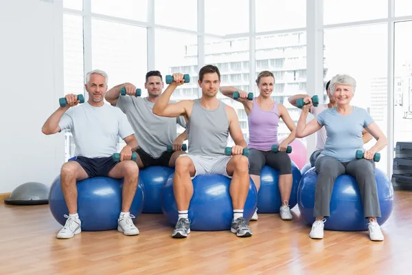 Lezione di fitness con manubri seduti su palline in palestra — Foto Stock