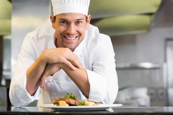 Sorrindo chef masculino com comida cozida na cozinha — Fotografia de Stock