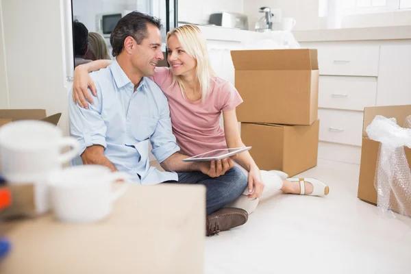 Couple using digital tablet amid boxes — Stock Photo, Image