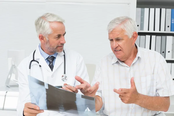 Male doctor explaining x-ray report to senior patient — Stock Photo, Image