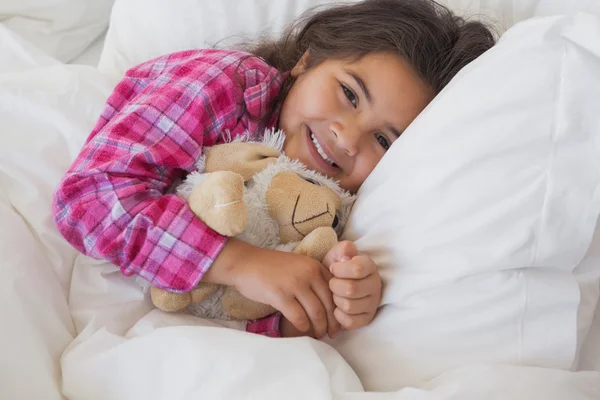 Menina sorridente com brinquedo de pelúcia descansando — Fotografia de Stock