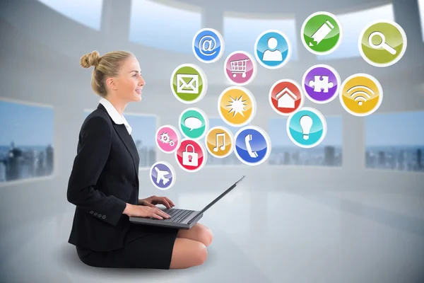 Businesswoman using laptop with app icons — Stock Photo, Image