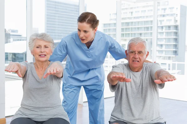 Female therapist assisting senior couple with exercises — Stock Photo, Image