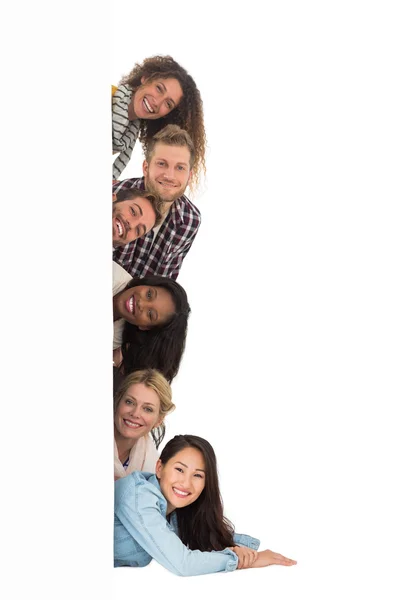 Happy group of young friends peeking from behind a wall — Stock Photo, Image