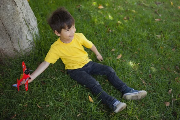 Mladý chlapec hraje s hračkou letadla v parku — Stock fotografie