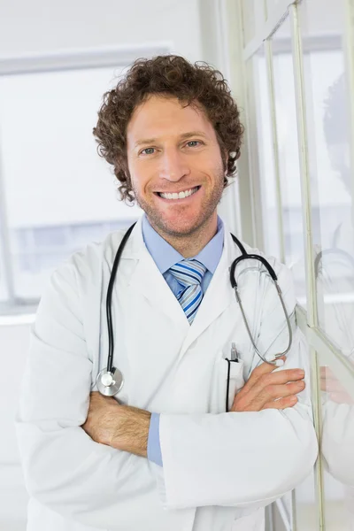 Komea mies lääkäri seisoo kädet ristissä sairaalassa — kuvapankkivalokuva