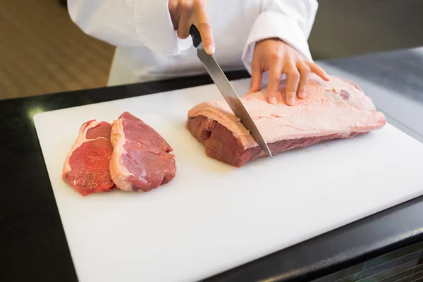 Mains coupant la viande dans la cuisine — Photo