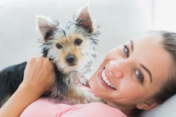 Mulher feliz abraçando seu terrier yorkshire no sofá — Fotografia de Stock