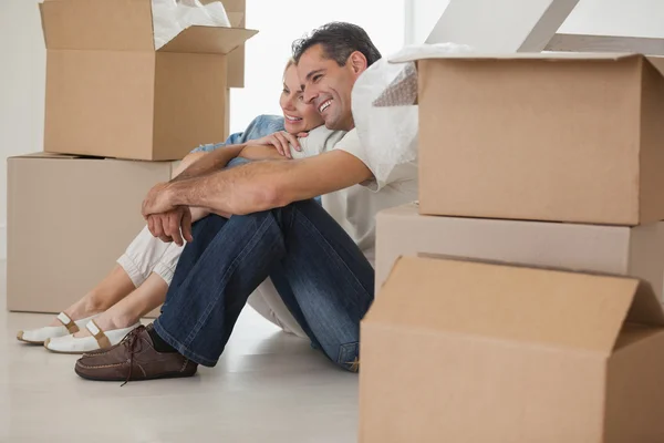 Couple sitting amid boxes in house — Stock Photo, Image