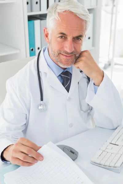 Mature male doctor at desk in the medical office — Stock Photo, Image