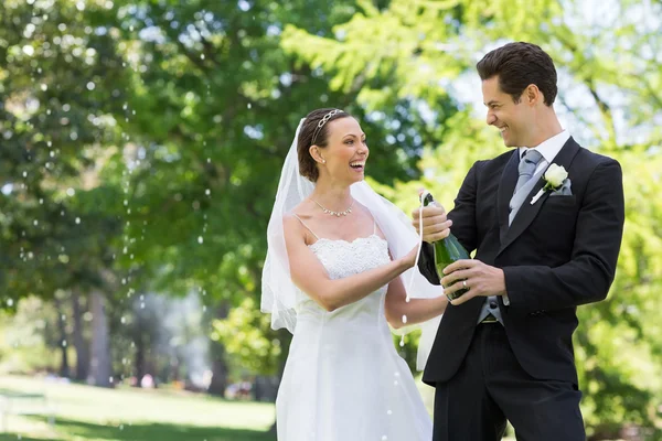Recién casada pareja abriendo botella de champán — Foto de Stock