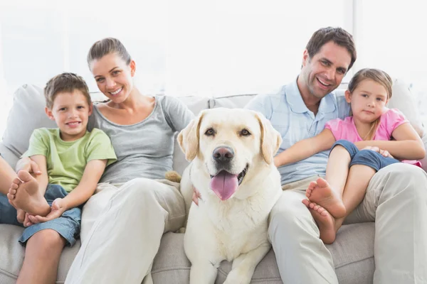 Счастливая семья сидит на диване со своим домашним лабрадором — стоковое фото