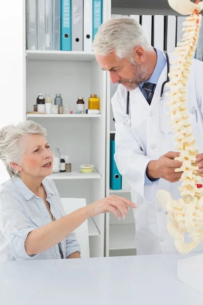 Médico varón explicando la columna vertebral al paciente mayor —  Fotos de Stock