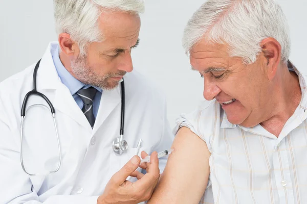 Médico injetando paciente idoso do sexo masculino — Fotografia de Stock