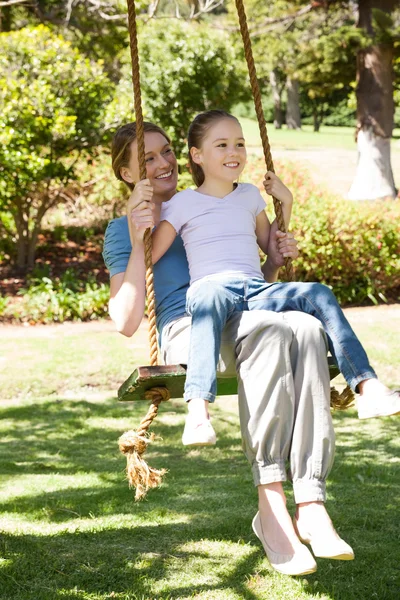 Joyeux mère et fille assis sur balançoire au parc — Photo