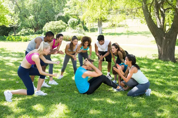 Amigos animando hombre haciendo sit ups —  Fotos de Stock