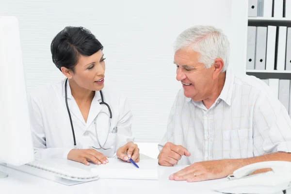 Female doctor with male patient reading reports — Stock Photo, Image