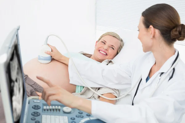 Doctor showing woman her baby on ultrasound — Stock Photo, Image