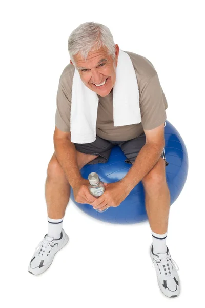 Heureux homme âgé avec bouteille d'eau assis sur la balle de fitness — Photo