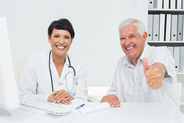 Felice paziente anziano gesticolando pollice in su con il medico — Foto Stock