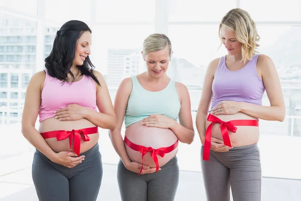 Pregnant women with red bow around bumps — Stock Photo, Image