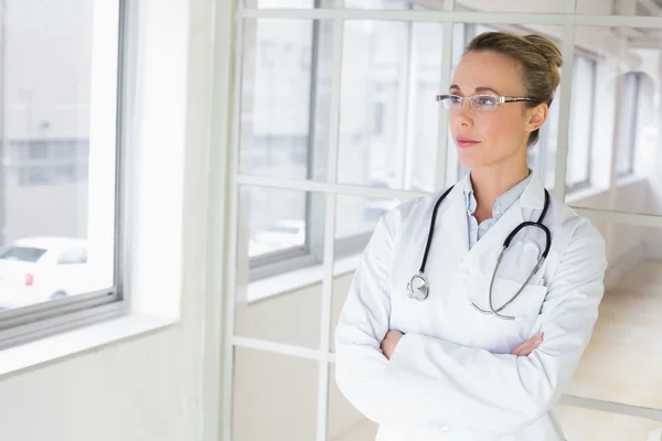 Ernstige vrouwelijke arts met gekruiste in ziekenhuis armen — Stockfoto