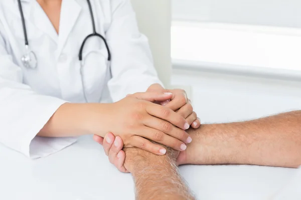 Close-up mid section of a doctor holding patients hands — Stock Photo, Image