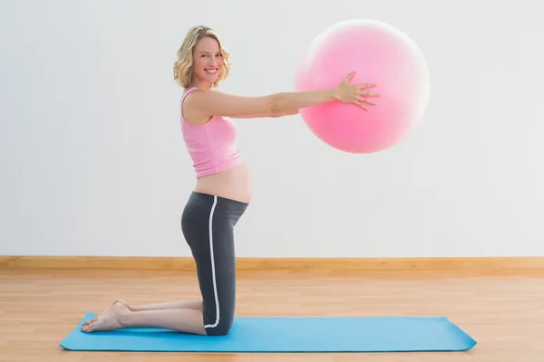 Щаслива блондинка вагітна жінка піднімає вправи м'яч — стокове фото