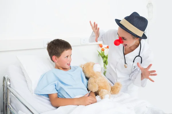 Доктор в костюме клоуна развлекает больного мальчика — стоковое фото