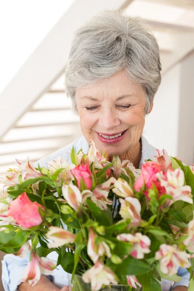 Retired woman holding bouquet of flowers and smiling Royalty Free Stock Photos