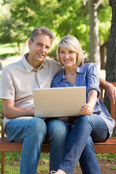 Couple with laptop sitting on bench Stock Photo