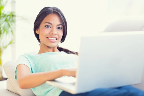 Girl lying on sofa using her laptop Stock Photo