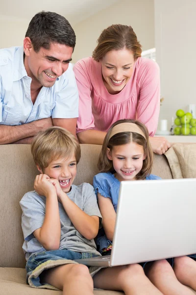 Ouders kijken naar kinderen met behulp van laptop — Stockfoto