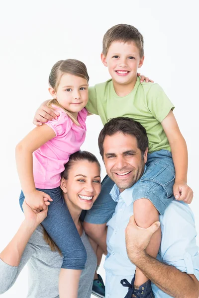 Parents giving their children piggyback ride smiling at camera Royalty Free Stock Photos