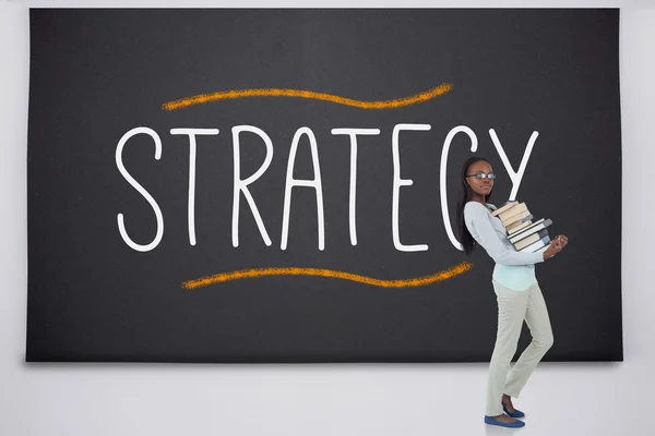 Student holding pile of books against the word strategy — Stock Photo, Image