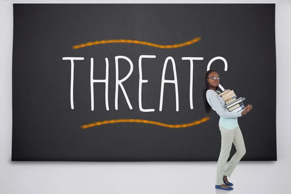 Student holding pile of books against the word threat — Stock Photo, Image