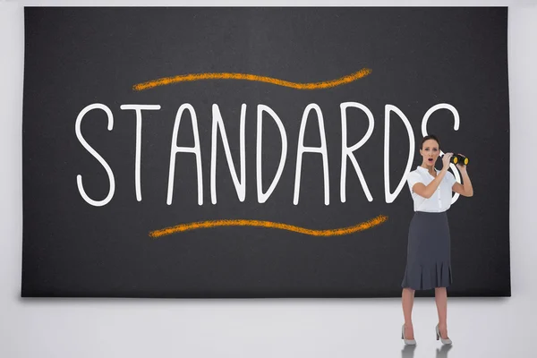 Shocked businesswoman with binoculars against the word standards — Stock Photo, Image