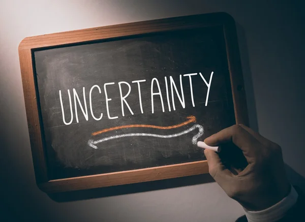 Hand writing Uncertainty on chalkboard — Stock Photo, Image