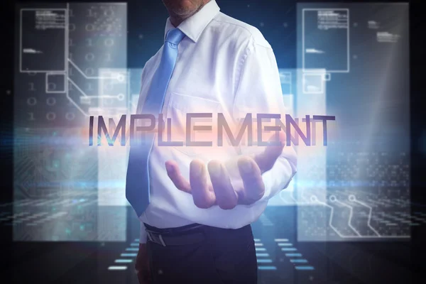 Businessman presenting the word implement — Stock Photo, Image