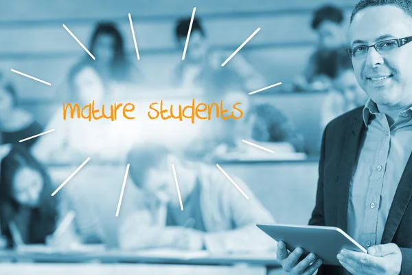 Mature students against lecturer standing in front of his class in lecture hall — Stock Photo, Image