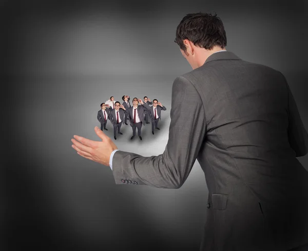 Businessman with hands out with tiny businessmen — Stock Photo, Image