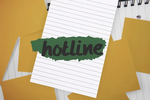 Hotline against yellow paper strewn over notepad — Stock Photo, Image