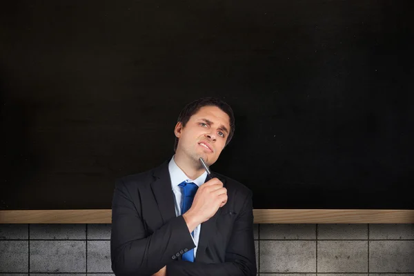 Thinking businessman holding pen — Stock Photo, Image