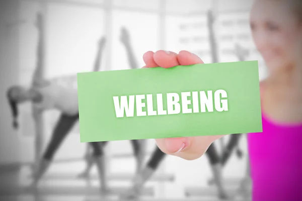 Fit blonde holding card saying wellbeing — Stock Photo, Image