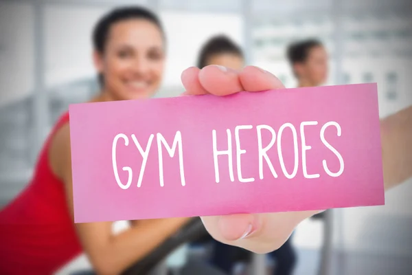 Woman holding pink card saying gym heroes — Stock Photo, Image