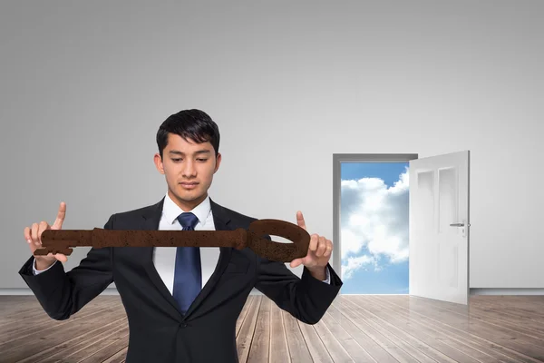 Unsmiling businessman carrying large key — Stock Photo, Image