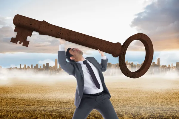 Unsmiling businessman carrying large key — Stock Photo, Image