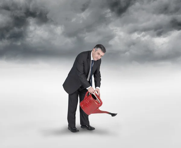 Mature businessman using watering can — Stock Photo, Image