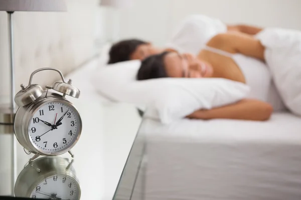 Couple lying in bed with focus on alarm clock — Stock Photo, Image