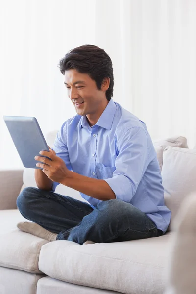 Happy man sitting on couch using tablet — Stock Photo, Image